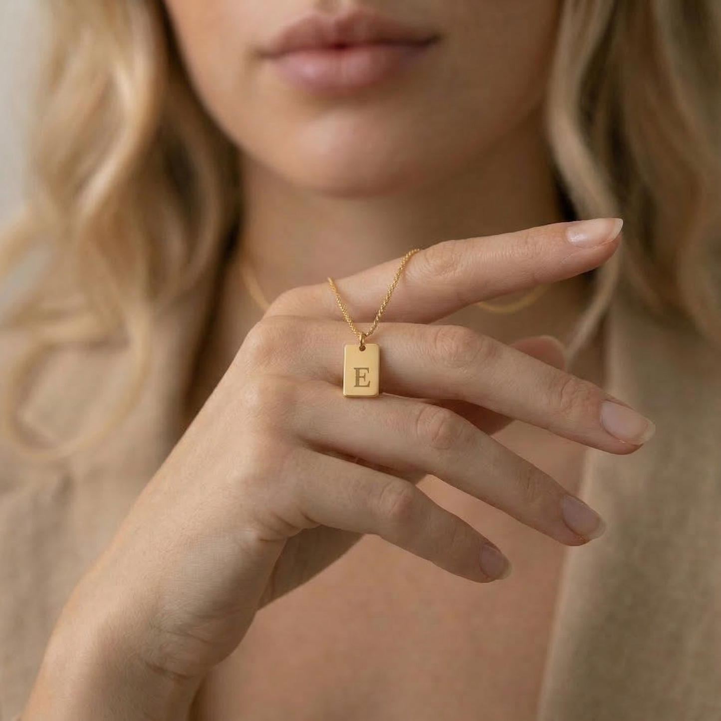 Close-up of engraved initial tag pendant in gold - Calioras