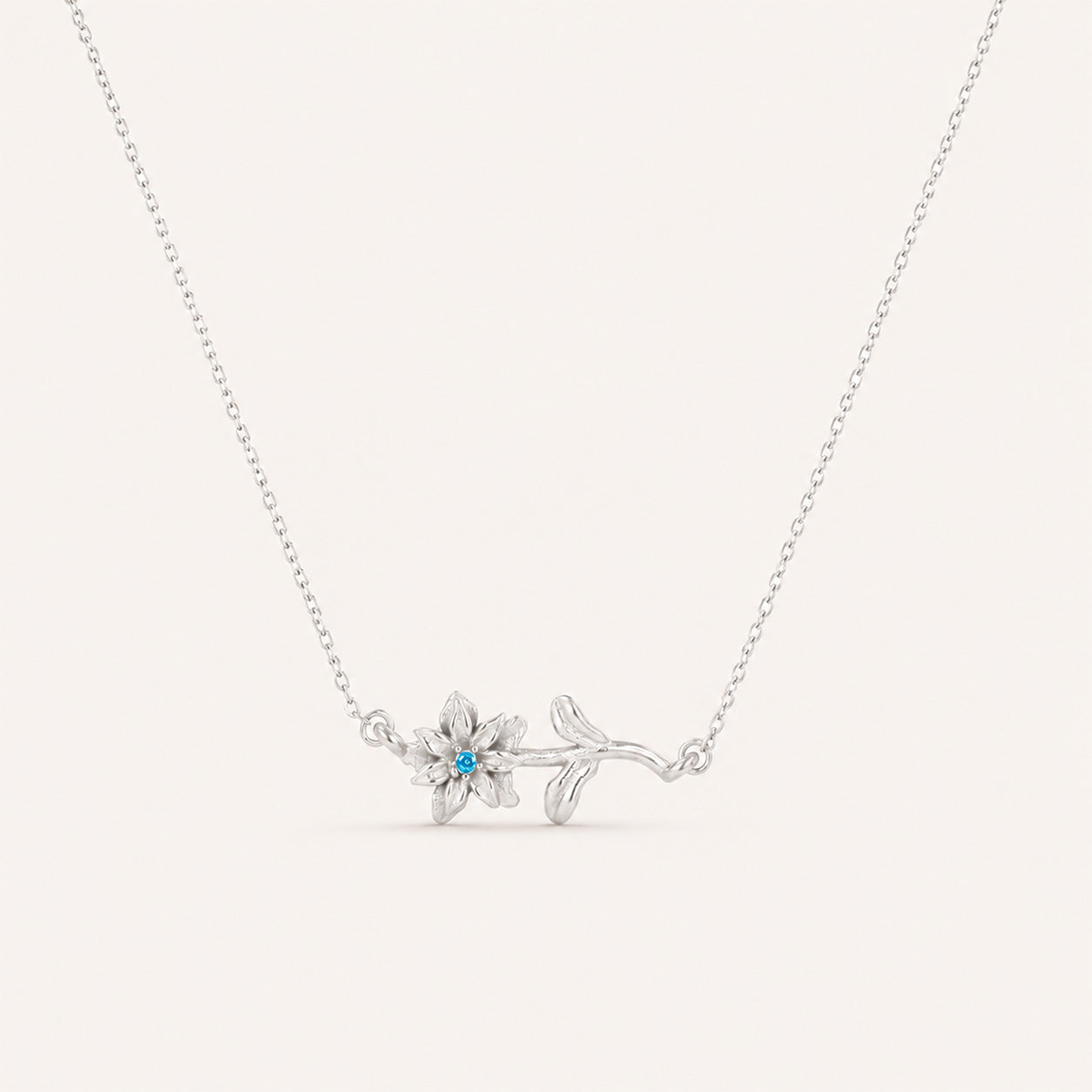 Birthstone flower necklace in silver on cream background
