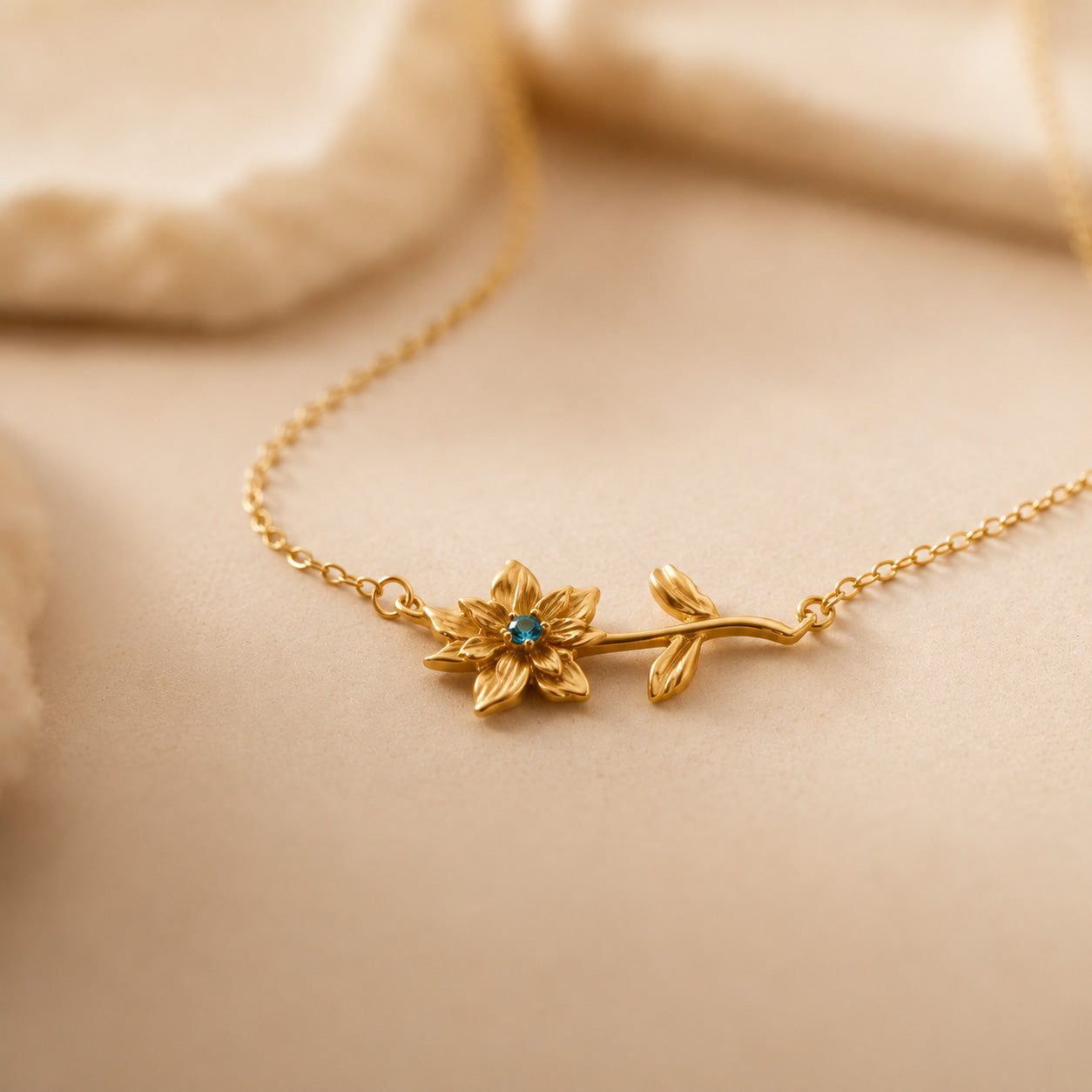 Birthstone flower necklace draped over cream still life