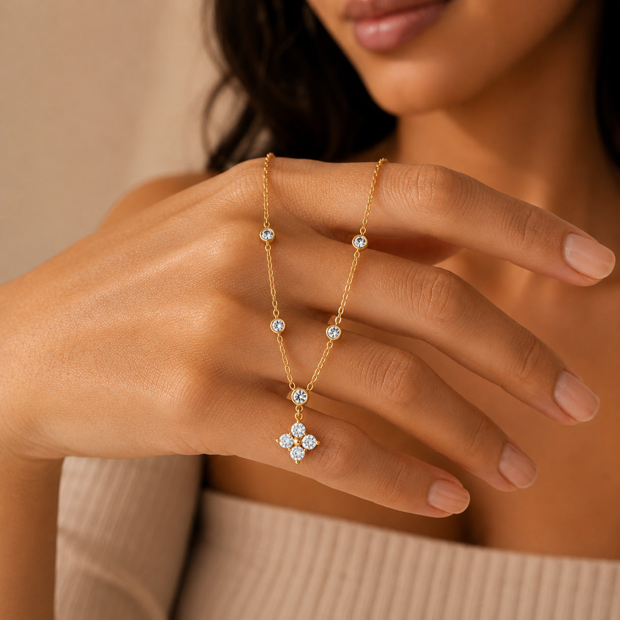 Gold crystal blossom station necklace draped over finger showing flower pendant and stations