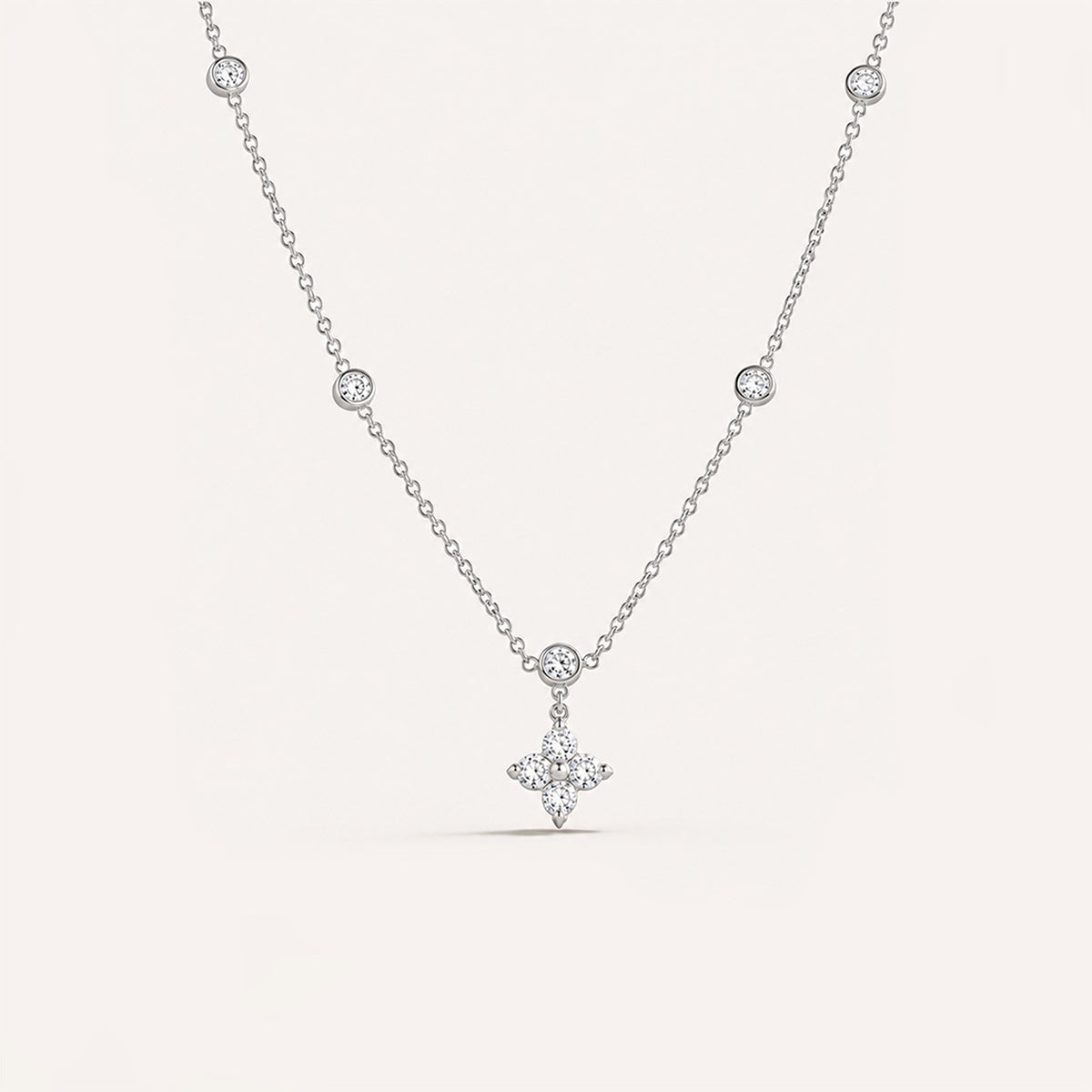 Tiny puffed plain cross necklace in silver on cream background