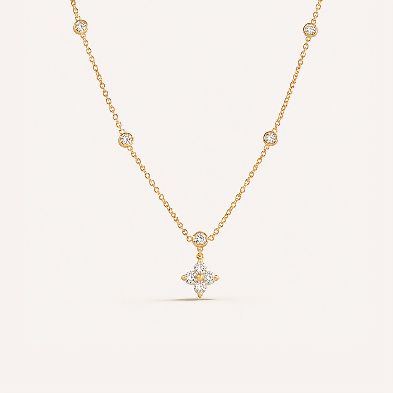 Crystal blossom station necklace in 18K gold with CZ flower pendant on cream background