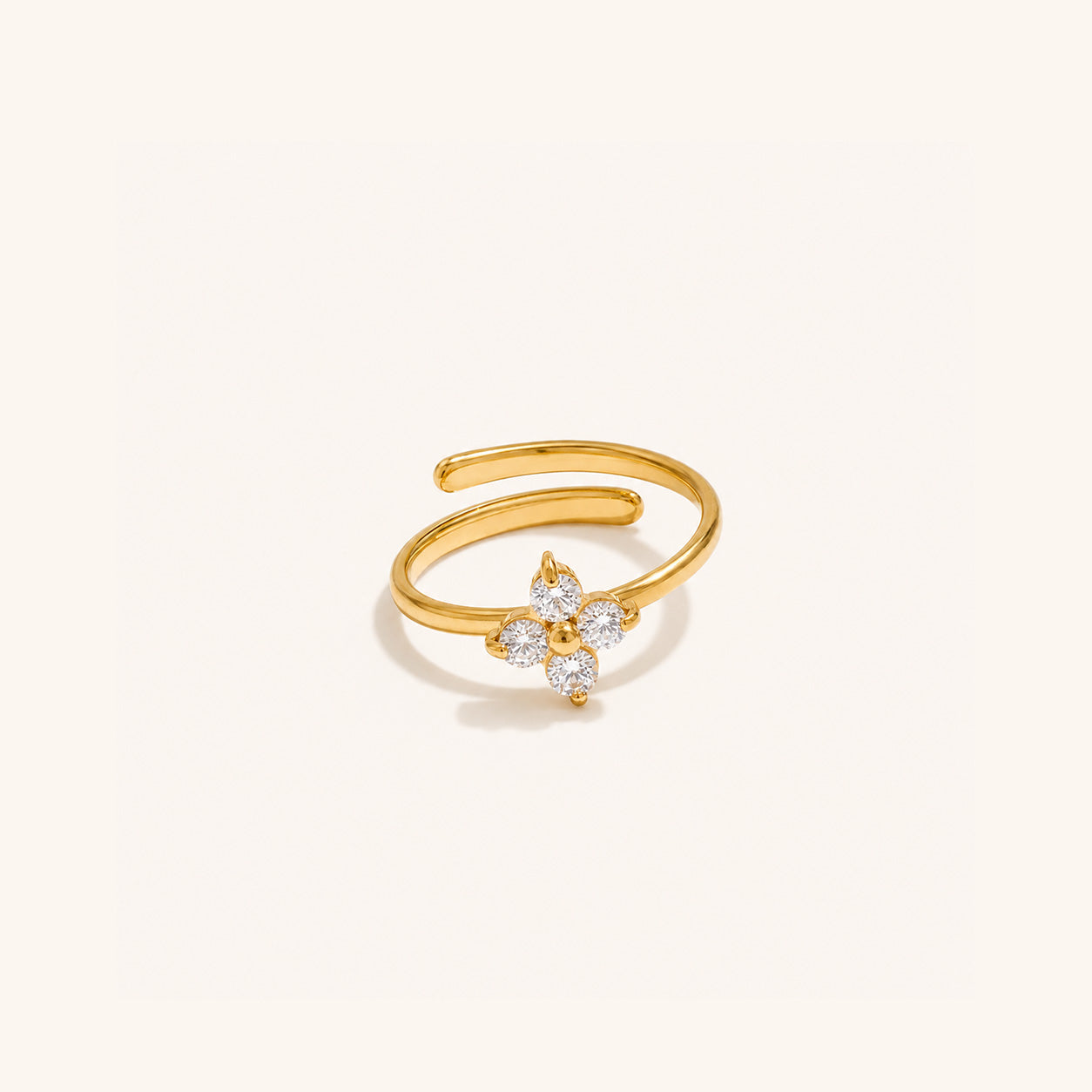 Crystal blossom ring in 18K gold with four CZ petals on cream background