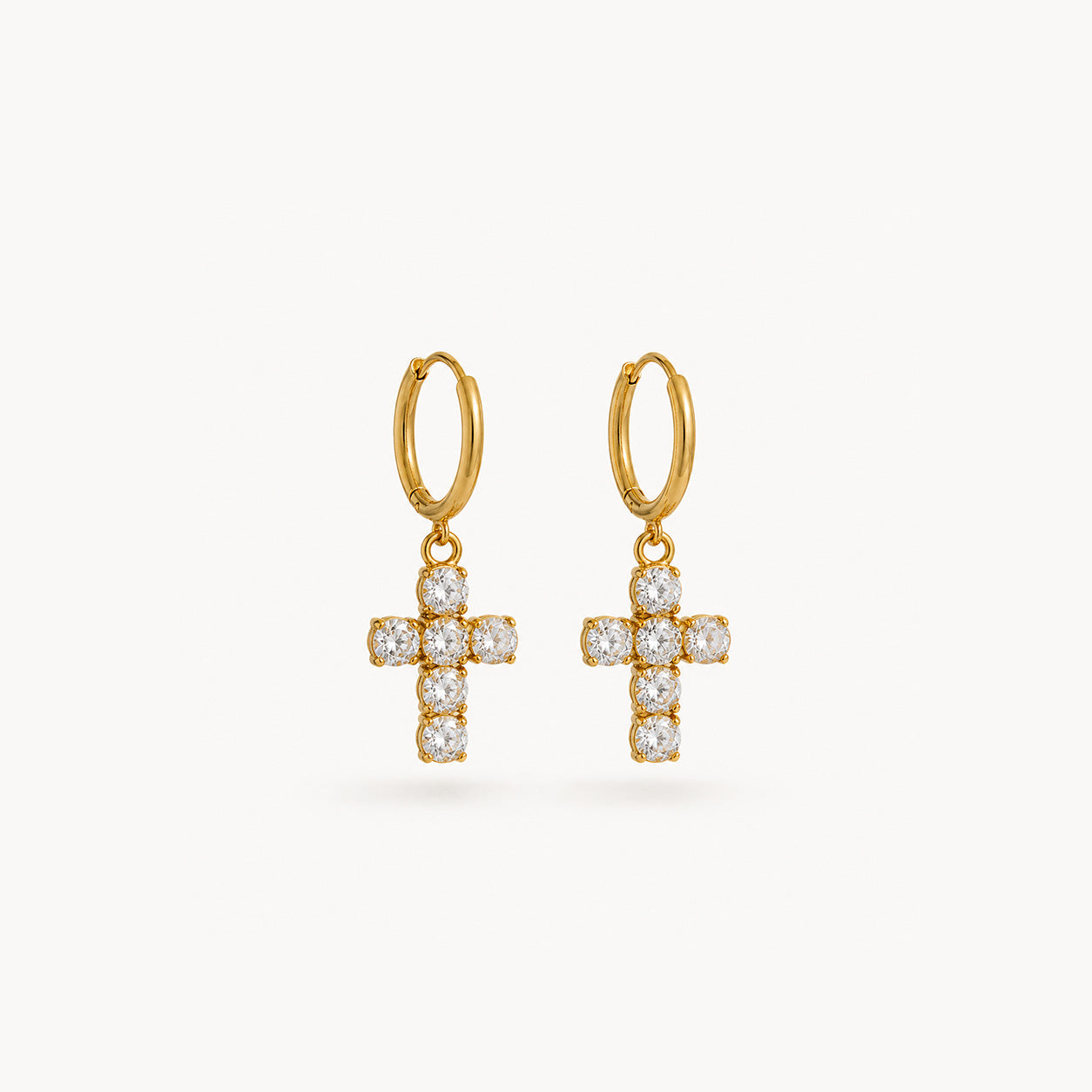 Crystal cross drop hoop earrings in 18K gold on cream background