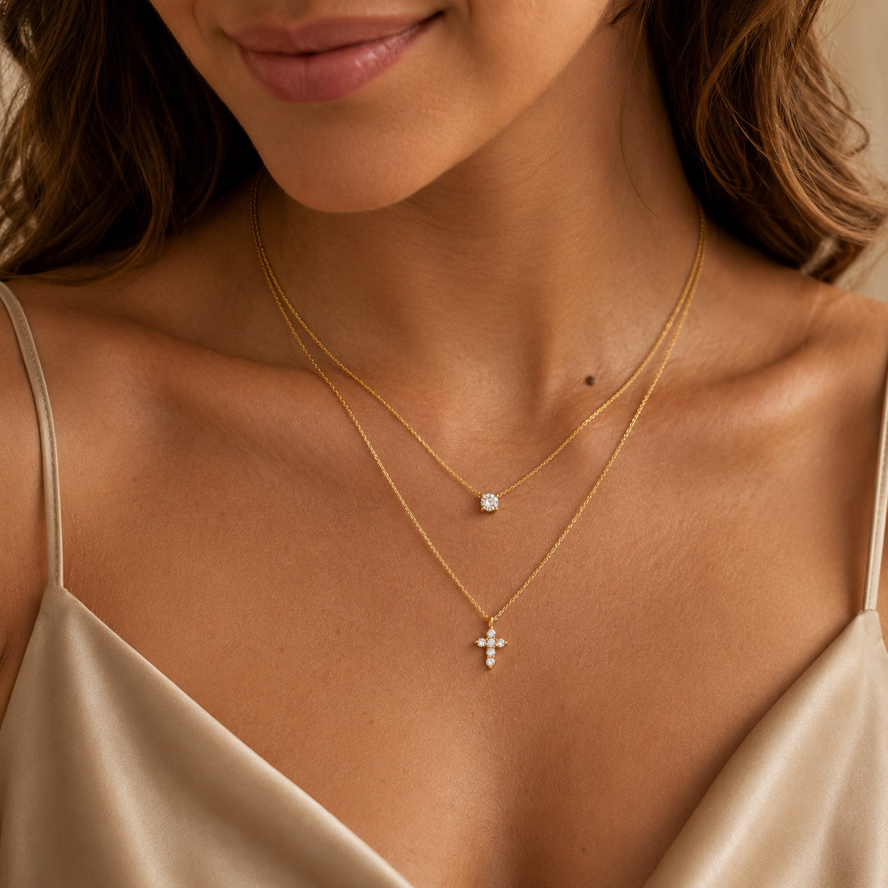 Woman wearing gold double layer necklace with crystal solitaire and petal cross
