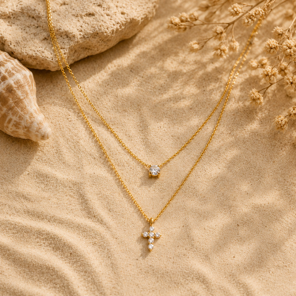 Double layer crystal and petal cross necklace draped over cream ceramic still life