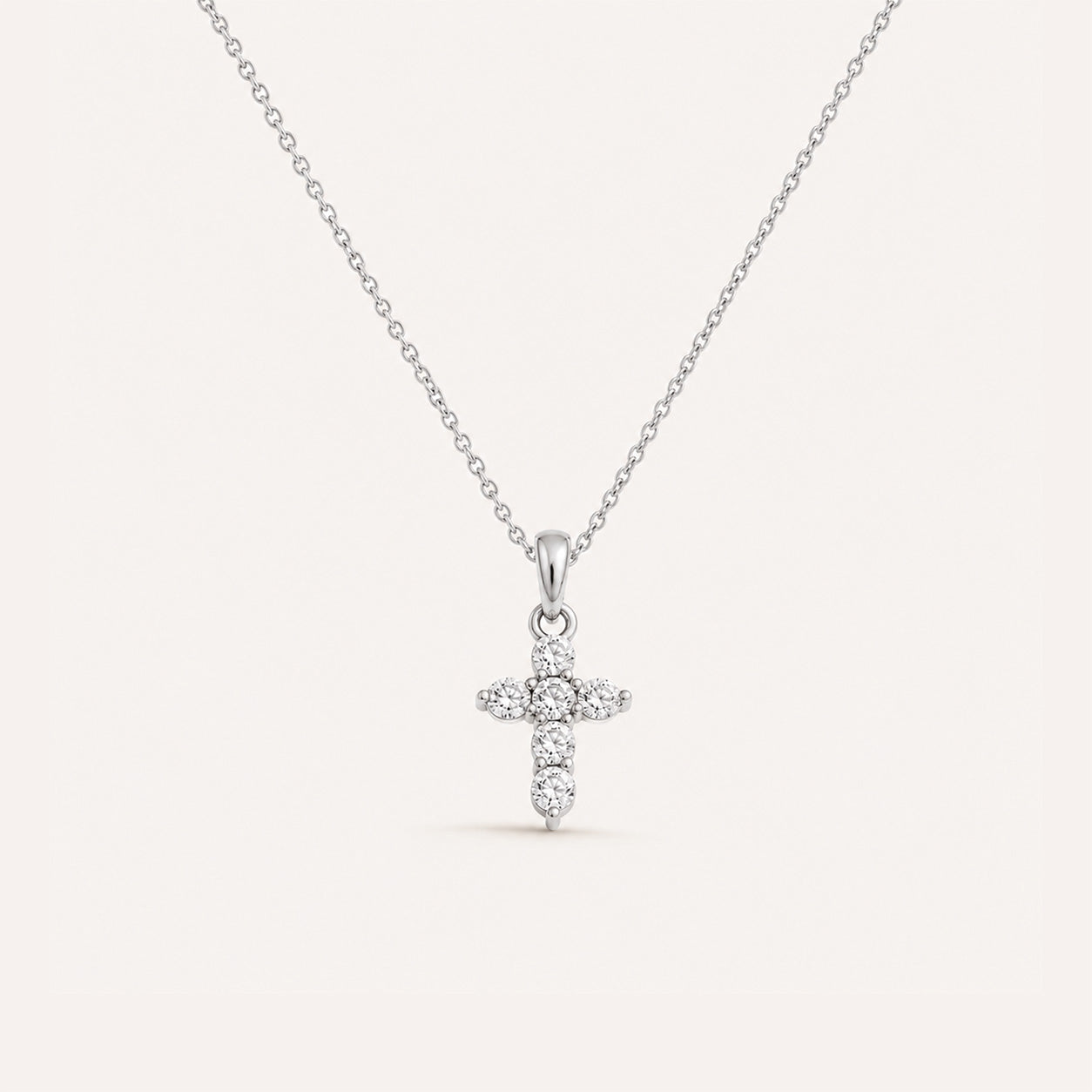 Mini crystal cross necklace in silver on cream background
