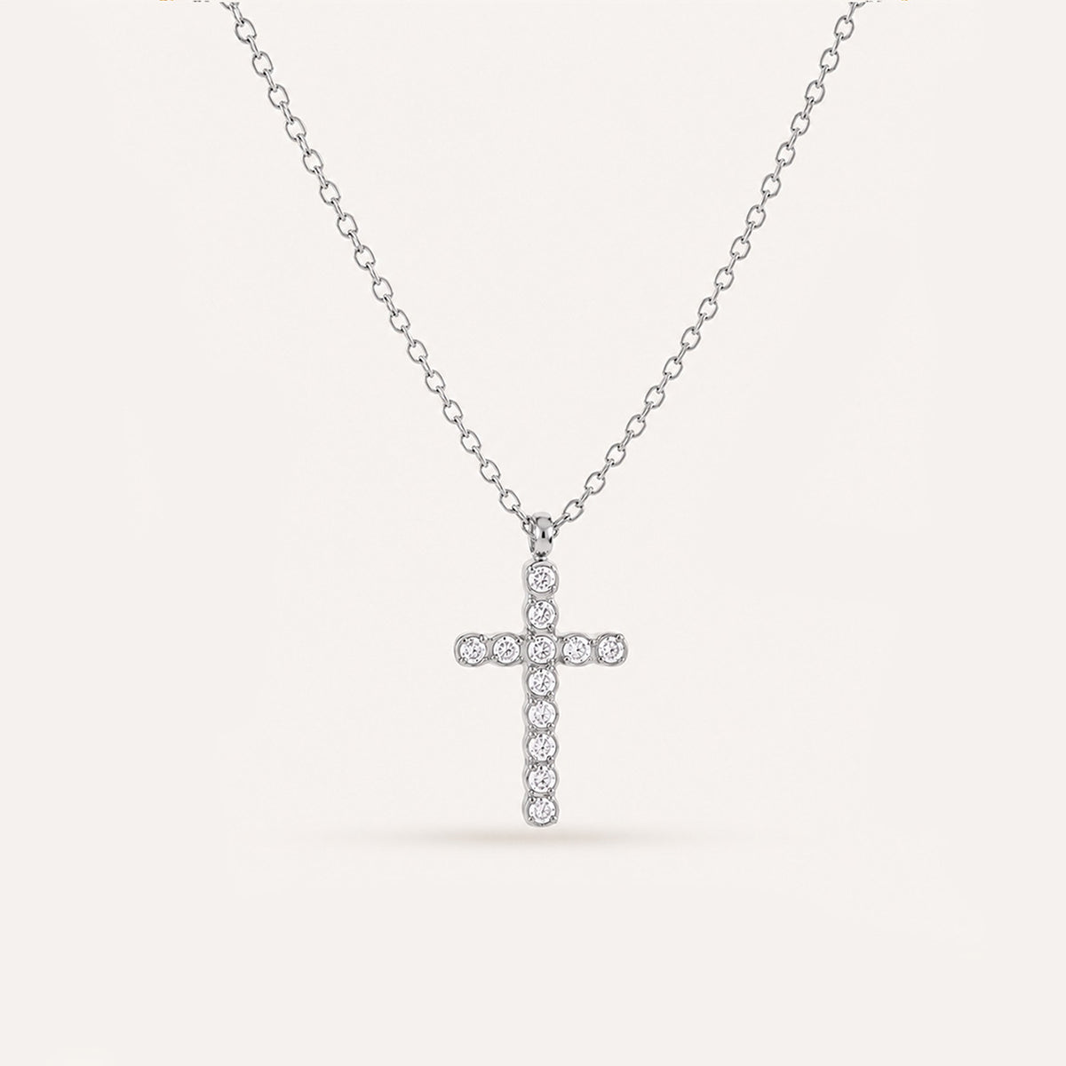 Mini crystal cross necklace in silver on cream background