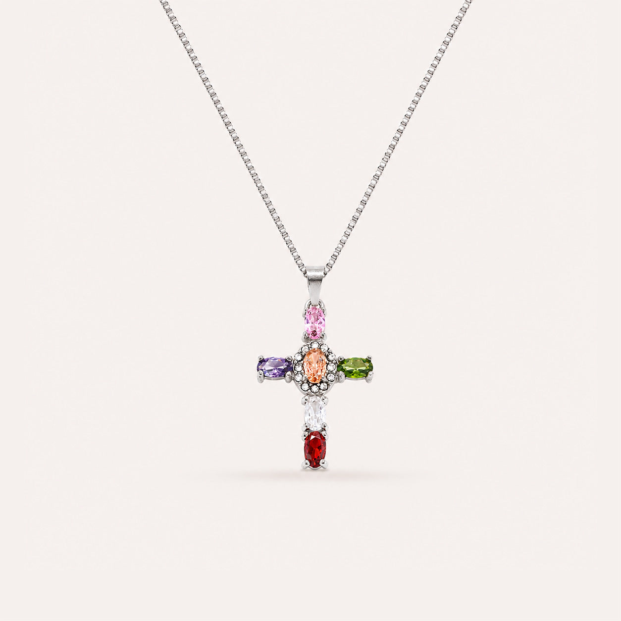 Oval gemstone halo cross necklace with rainbow crystal cross in silver on cream background