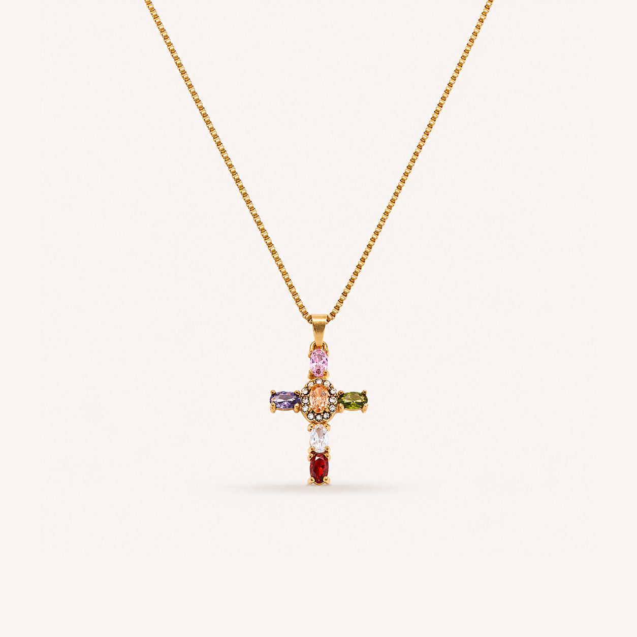 Oval gemstone halo cross necklace with rainbow crystal cross in 18K gold on cream background