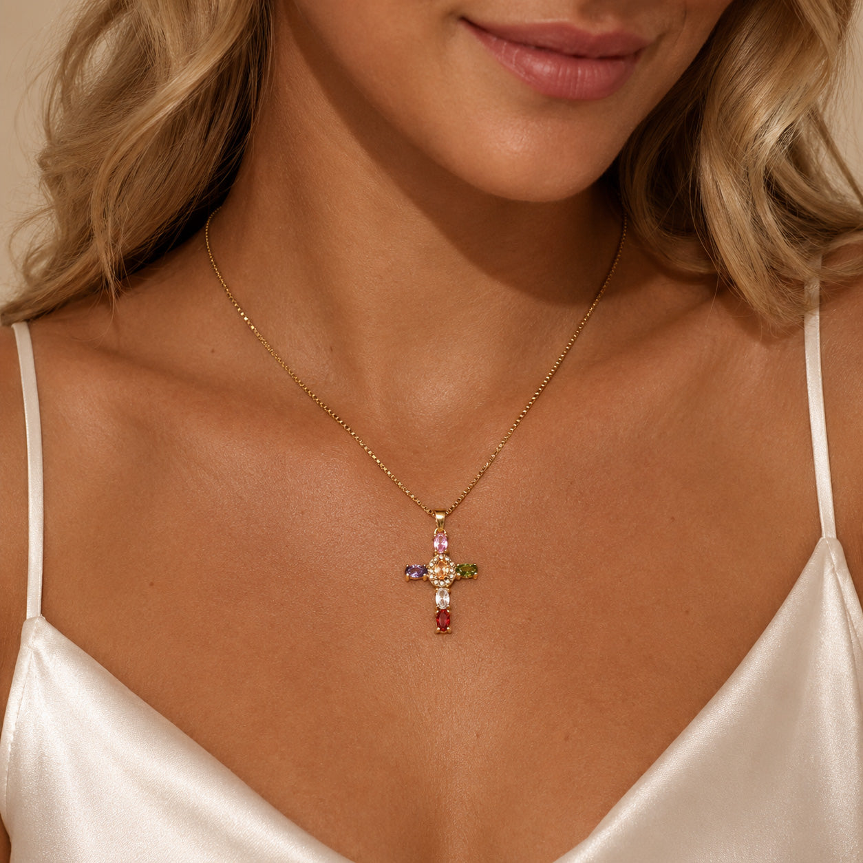 Woman wearing gold gemstone halo cross necklace with rainbow crystal pendant