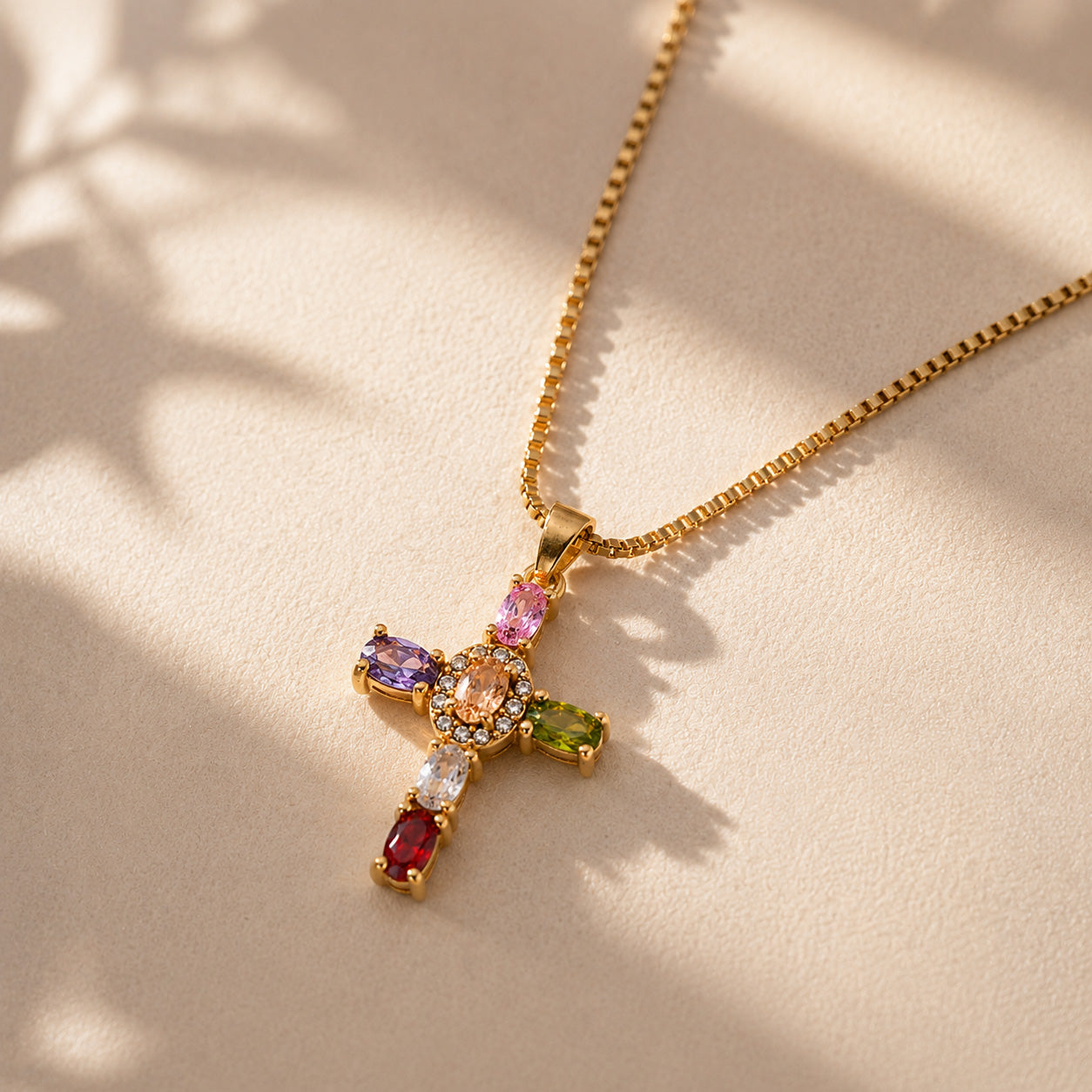 Gemstone halo cross necklace draped over cream ceramic still life