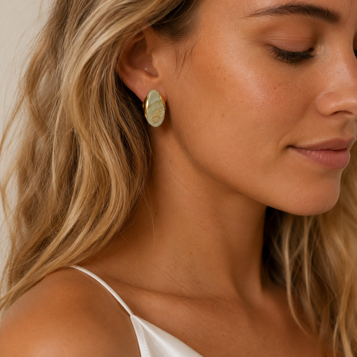 Close up of gold oval birthstone stud earring on ear