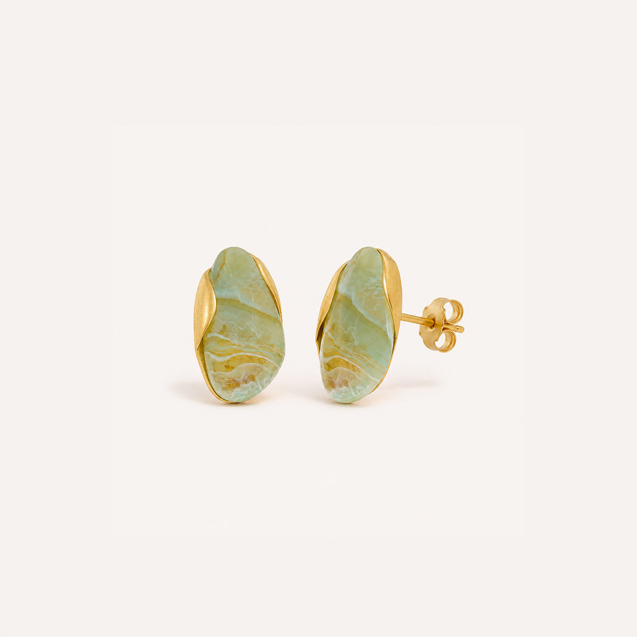 Oval stone birthstone stud earrings in 18K gold on cream background