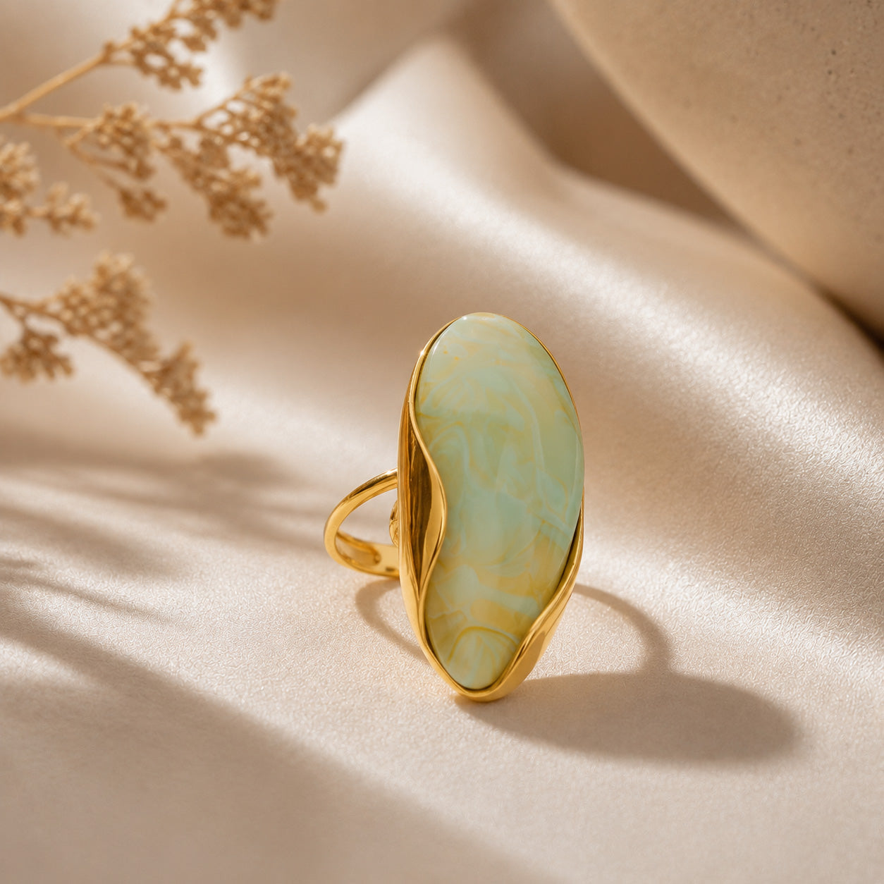 Oval stone birthstone ring resting on cream ceramic still life