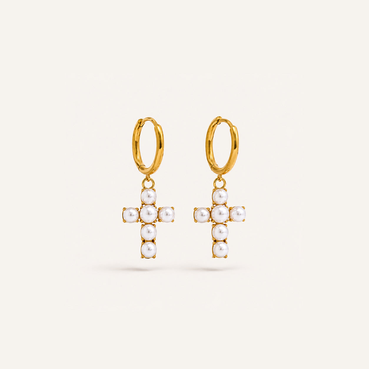 Pearl cross drop hoop earrings in 18K gold on cream background
