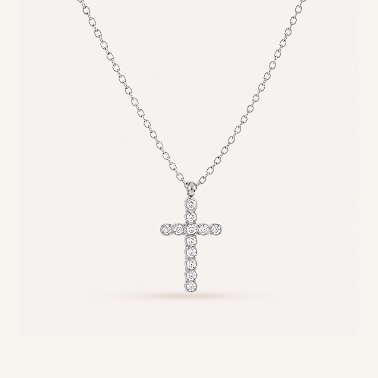 Round crystal cross necklace in silver on cream background