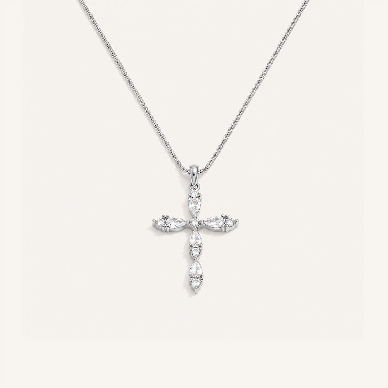Teardrop crystal cross necklace in silver on cream background