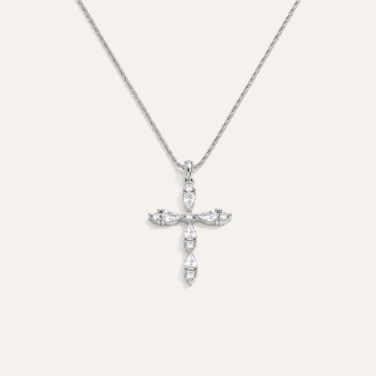 Teardrop crystal cross necklace in silver on cream background