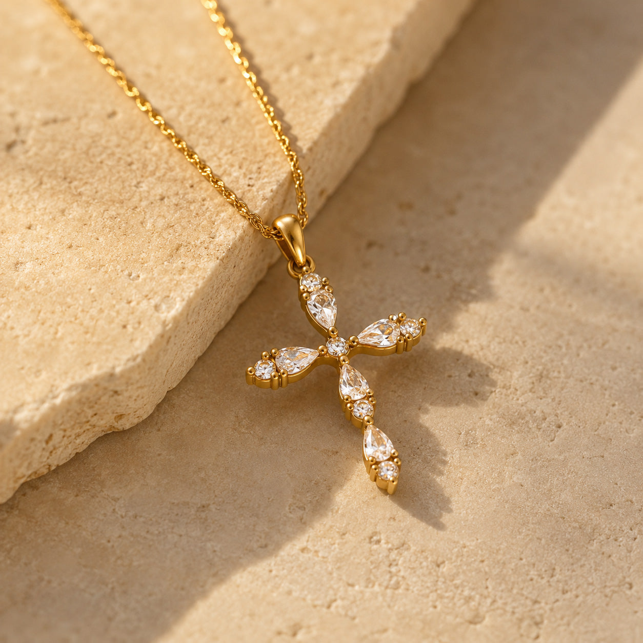 Teardrop crystal cross necklace draped over cream ceramic still life