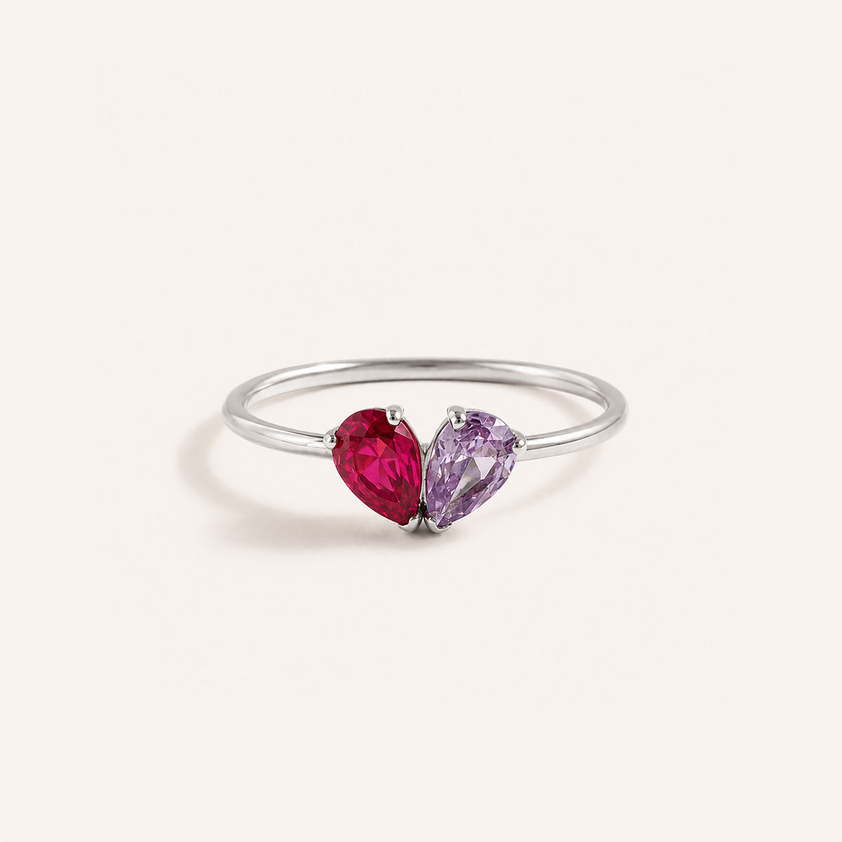Toi et moi teardrop birthstone ring in silver with ruby and amethyst pear stones on cream background