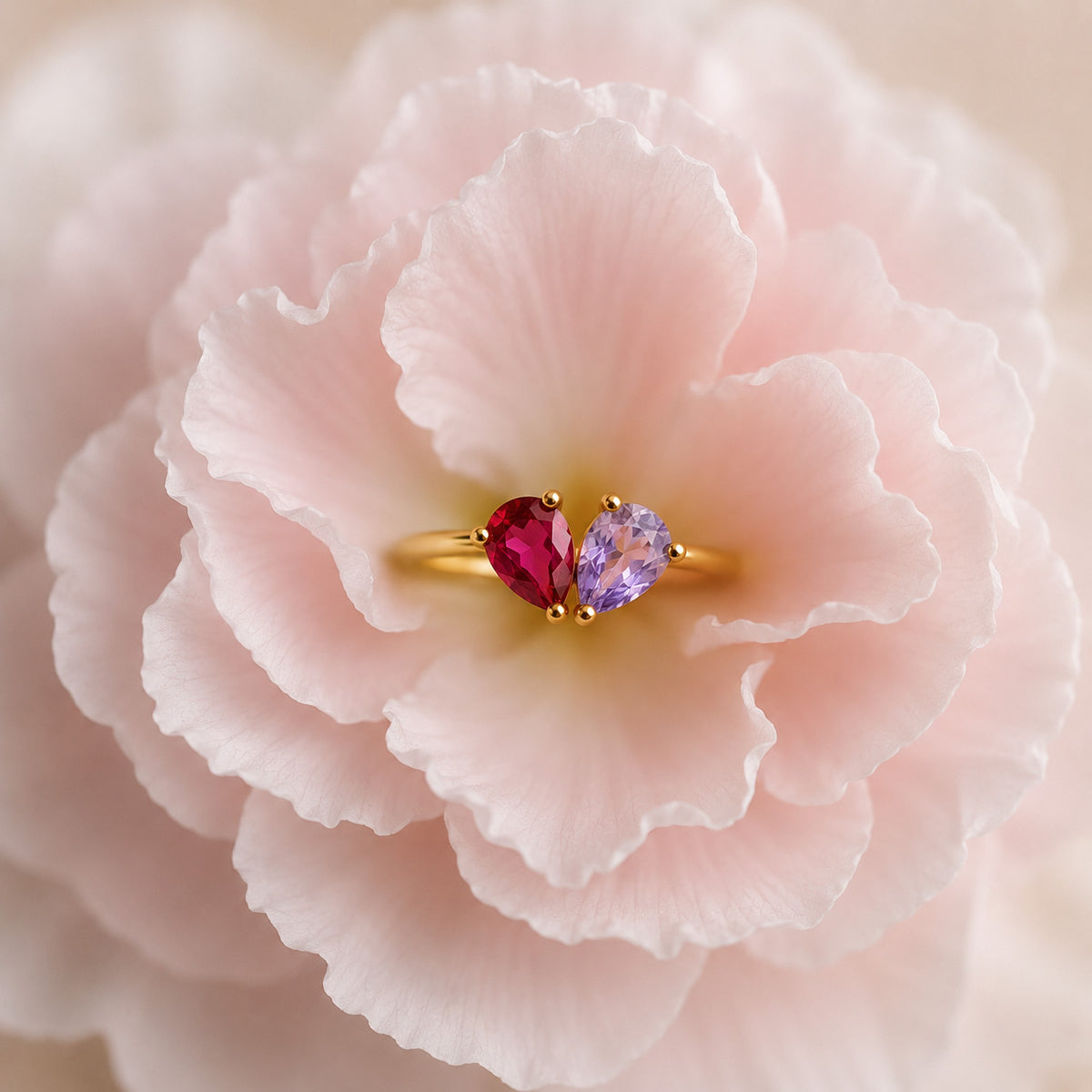 Gold toi et moi teardrop birthstone ring resting on a soft pink rose still life